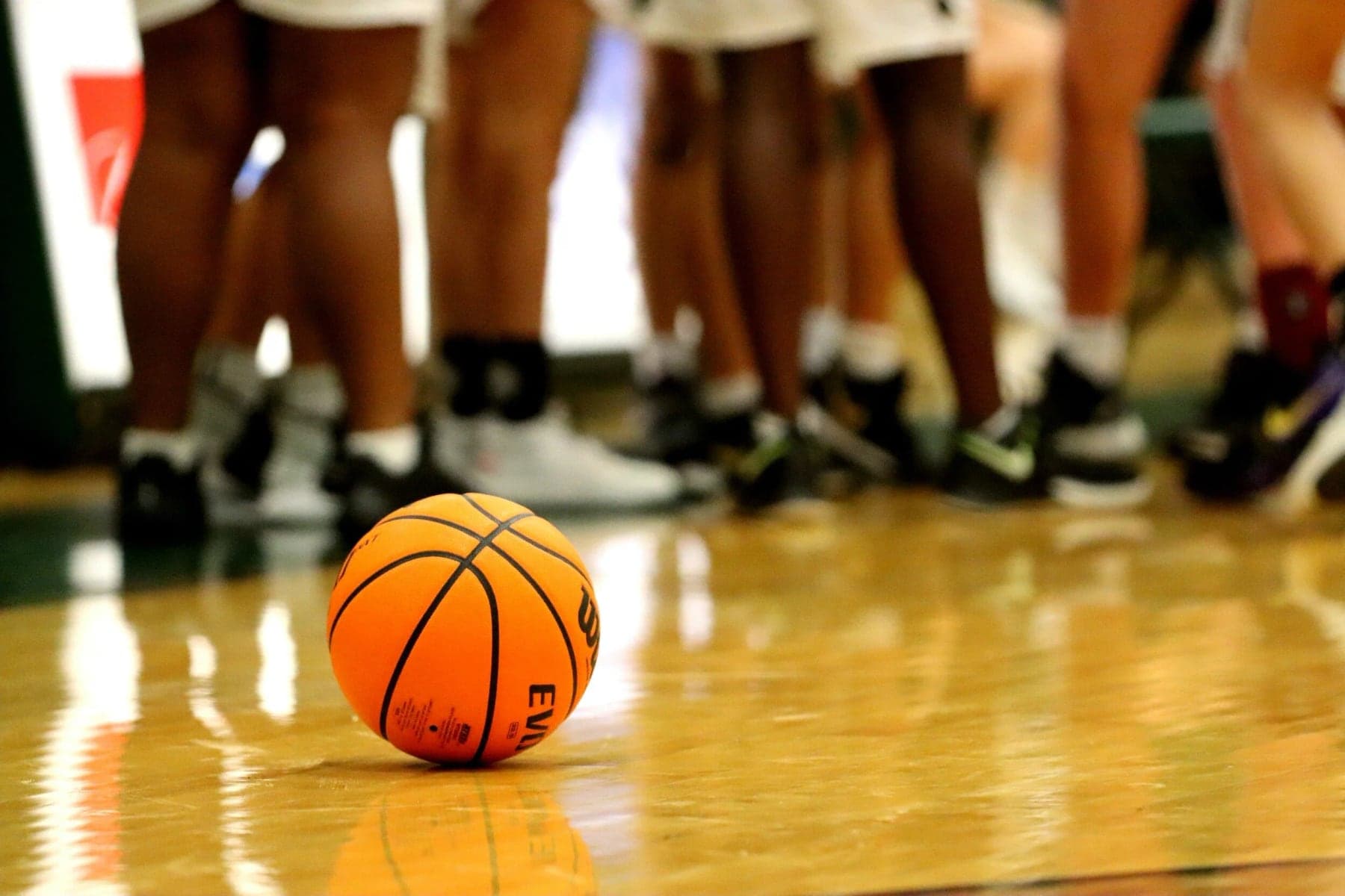 A basketball on the court at players' feet